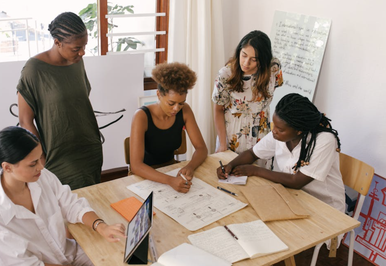 Five people work around a desk looking at papers