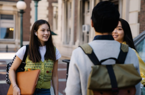 Three students stand on campus and chat