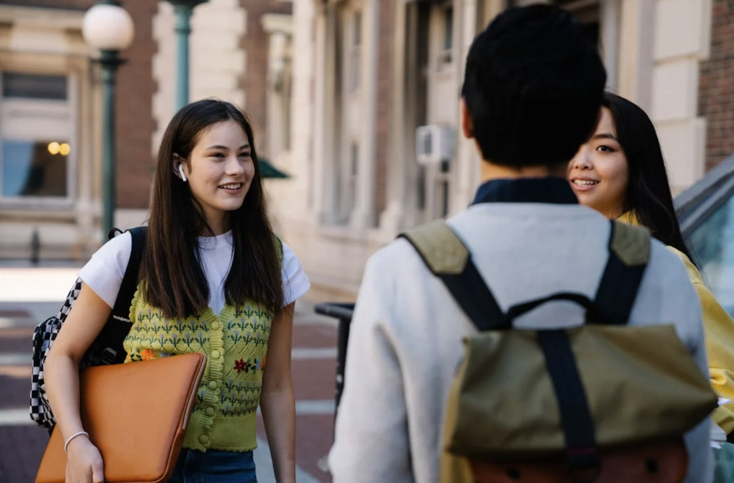 Three students stand on campus chatting