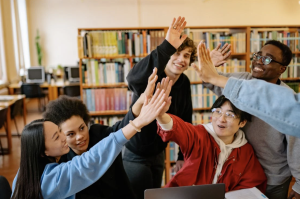 Students sit in a library and high five one another