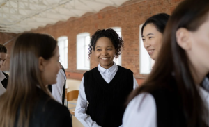 Women standing in a large room smile at one another
