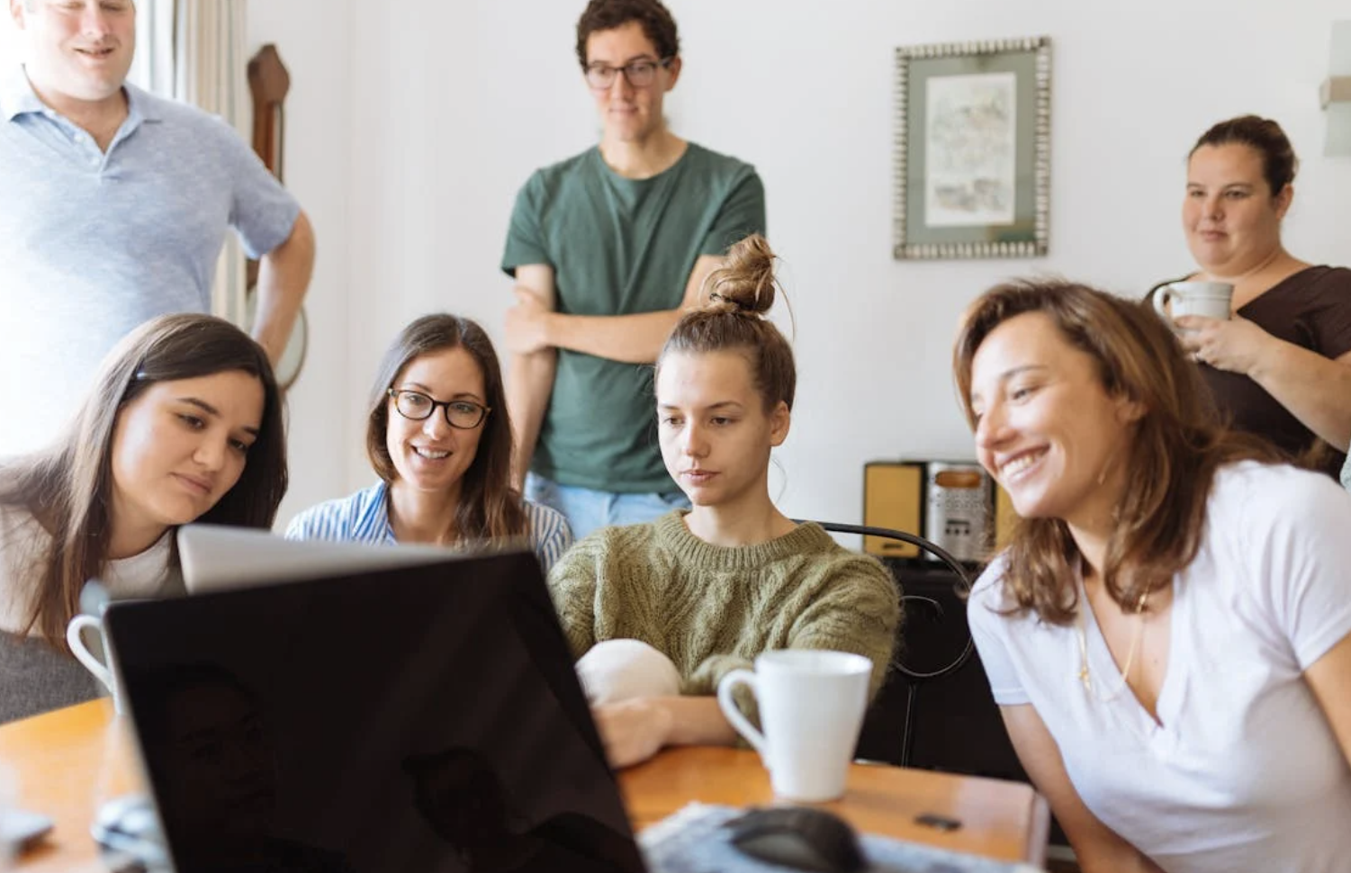 People gather around a laptop on a table